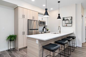 a kitchen with a large island with stools and a stainless steel refrigerator